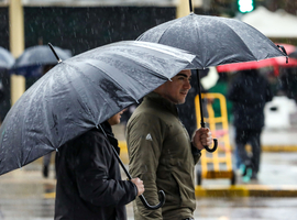 Personas caminan bajo la lluvia protegidos con sus paraguas